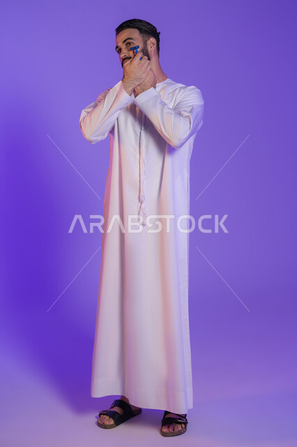 ماكينة حلاقة عصرية للعناية باللحية, الحفاظ على الأناقة والنظافة الشخصية، العناية بالبشرة والاهتمام بالمظهر الخارجي، بورتريه لرجل عربي خليجي اماراتي يرتدي الكندورة الاماراتية و يمسك الشفرة, خلفية بنفسجية