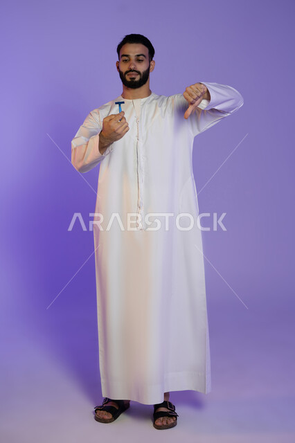 الإشارة بعلامة عدم القبول والجودة السيئة، الحفاظ على الأناقة والنظافة الشخصية، العناية بالبشرة والاهتمام بالمظهر الخارجي، بورتريه لرجل عربي خليجي اماراتي يرتدي الكندورة الاماراتية و يمسك شفرة حلاقة, خلفية بنفسجية