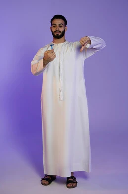الإشارة بعلامة عدم القبول والجودة السيئة، الحفاظ على الأناقة والنظافة الشخصية، العناية بالبشرة والاهتمام بالمظهر الخارجي، بورتريه لرجل عربي خليجي اماراتي يرتدي الكندورة الاماراتية و يمسك شفرة حلاقة, خلفية بنفسجية