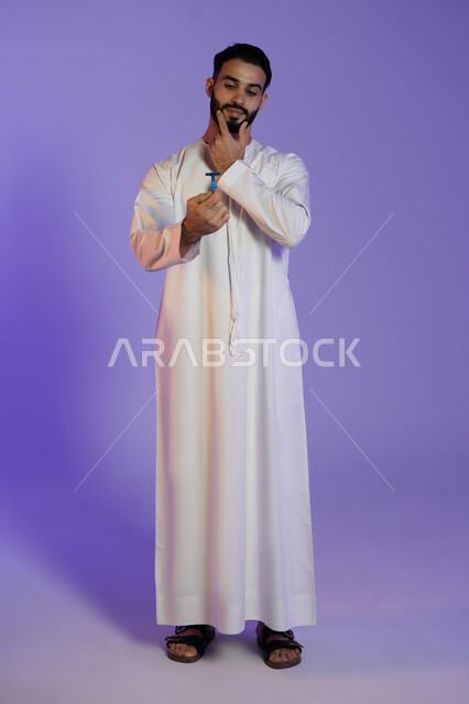 لمسة نهائية للحصول على مظهر أنيق, لحظة تركيز قبل الحلاقة, الحفاظ على الأناقة والنظافة الشخصية، العناية بالبشرة والاهتمام بالمظهر الخارجي، بورتريه لرجل عربي خليجي اماراتي يرتدي الكندورة الاماراتية و يمسك الشفرة, خلفية بنفسجية