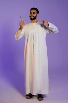حماية السن من التسوس، مفهوم العناية بصحة ونظافة الفم، الاهتمام بالأناقة والمظهر الخارجي، المحافظة على ابتسامة بيضاء، بورتريه لرجل عربي خليجي اماراتي يرتدي الكندورة الاماراتية و يشير باصبع السبابة الى فرشاة الأسنان، خلفية بنفسجية