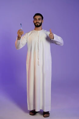 Hand gesture indicating admiration, a sign of distinction and quality, maintaining elegance and personal hygiene, skin care and attention to one's appearance, a portrait of an Emirati Gulf Arab man wearing an Emirati kandura holding a brush, raising his thumb as a like sign, purple background