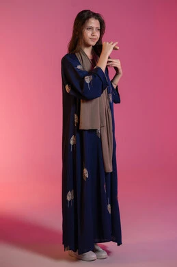 تصفيف و تسريح الشعر, الاهتمام بالجمال والأناقة، العناية بالنظافة الشخصية، بورتريه لامرأة عربية خليجية اماراتية مبتسمة ترتدي عباءة زرقاء و تقوم بتمشيط شعرها باستخدام الفرشاة، خلفية وردية