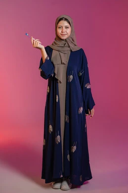 الوقوف باستقامة و اعتدال, روتين نظافة الفم اليومية، تجنب التسوس وأمراض اللثة, التأكد من النظافة بعد تناول الطعام, بورتريه لامرأة عربية خليجية اماراتية محجبة ترتدي عباءة زرقاء تمسك بيدها فرشاة الأسنان, خلفية وردية