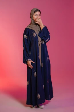 استخدام ماسك تنظيف المسام، العناية والاهتمام بنضارة وتحسين البشرة، التخلص من الرؤوس السوداء والجلد الميت، بورتريه لامرأة عربية خليجية اماراتية محجبة ترتدي عباءة زرقاء تقوم بوضع لصقات الأنف، خلفية وردية