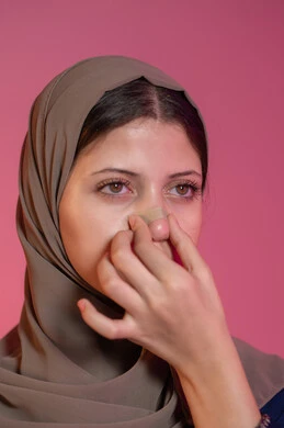 استخدام ماسكات تنظيف المسام ومكونات تجميلية نسائية، العناية والاهتمام بنضارة وتحسين البشرة، التخلص من الرؤوس السوداء والجلد الميت، بورتريه مقرب لامرأة عربية خليجية اماراتية محجبة تقوم بوضع لصقات الأنف، خلفية وردية