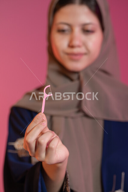 بورتريه مقرب ليد امرأة عربية خليجية اماراتية تحمل نكاشة أسنان, الاهتمام والعناية بنظافة وصحة الفم, تجنب التسوس وأمراض اللثة, التأكد من النظافة بعد تناول الطعام, خلفية غير واضحة للشابة