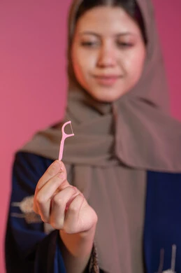 بورتريه مقرب ليد امرأة عربية خليجية اماراتية تحمل نكاشة أسنان, الاهتمام والعناية بنظافة وصحة الفم, تجنب التسوس وأمراض اللثة, التأكد من النظافة بعد تناول الطعام, خلفية غير واضحة للشابة