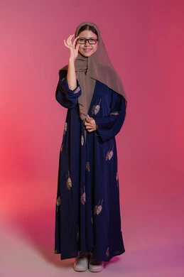 Correcting and improving vision, the pleasure of shopping in the Emirates, buying new eyeglasses, the concept of weak vision, a portrait of a smiling veiled Emirati Gulf Arab woman wearing a blue abaya choosing glasses that suit her facial features, pink background