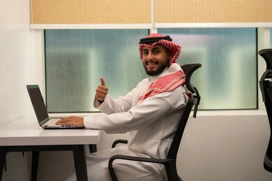 ايماءات الجودة و الامتياز والتميز، الموافقة والرضا و القبول، استخدام الكمبيوتر لإرسال البريد الإلكتروني، دمج التقنيات الحديثة و المتطورة مع العمل, مهن و أعمال مكتبية إدارية, رجل عربي خليجي سعودي يرتدي الثوب التقليدي و الشماغ و يقوم باستخدام اللابتوب و يرفع اصبع الابهام باشارة اللايك