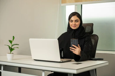 متابعة أخبار الشركات العالمية، تصفح وسائل التواصل الاجتماعي، إتمام المهام عبر الإنترنت، إدارة شؤون الأعمال و تنظيمها, سيدة عربية خليجية سعودية محجبة ترتدي عباءة سوداء و تستخدم جهاز اللابتوب و الموبايل, نمط الحياة في بيئة العمل الراقية, إيماءات الاندماج و التركيز