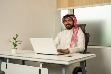 استخدام الحاسب و التقنية في مجال الاعمال، مفهوم التركيز و الدقة في الإنجاز، مهنة و وظيفة سعودية مكتبية, إتمام مهام العمل في المكتب، موظف عربي خليجي سعودي يرتدي الثوب التقليدي و الشماغ و يقوم باستخدام اللابتوب