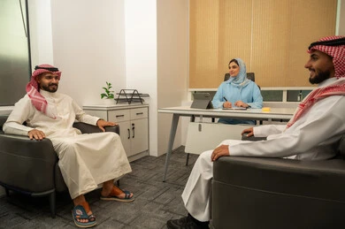 علاقات إجتماعية بين الزملاء, مهن ووظائف ادارية, العمل الجماعي و التعاون، فريق عربي خليجي سعودي مكون من رجلين يرتديان الثوب التقليدي و الشماغ و سيدة محجبة ترتدي العباءة الزرقاء و أمامها جهاز التابلت, مناقشة المشاريع و متابعة الإستراتيجيات، جمع البيانات و حل المشكلات