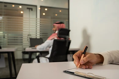تسجيل الملاحظات و النتائج, ملفات و وثائق خاصة بالعمل، الاحترافية والتفاني في الإنجاز،  صورة مقربة ليد رجل عربي خليجي سعودي يرتدي الثوب التقليدي و يقوم بالكتابة على ورق أبيض, مهن و وظائف مكتبية, الحياة المهنية السعودية, دراسة و تتبع المشاريع