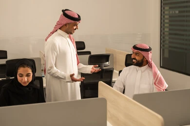 شرح واعطاء الخبرات بين الزملاء، التركيز والعمل المتقن, الحوارات والنقاشات ضمن الفريق,تطوير الاعمال والشركات, اجتماع عمل وانجاز المشاريع, مناقشة الخطط وشرح مهام الاعمال, زملاء عمل عرب سعوديين خليجيين يرتدون الزى التقليدي والشماغ يتبادلان الحديث