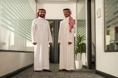 مفهوم التحاور وتبادل الأراء في خطط إنجاز الأعمال، مهن ووظائف إدارية مكتبية، مناقشة خطط المشاريع ،شرح مهام العمل ، الحوارات والنقاشات ضمن الفريق,تطوير الاعمال والشركات, موظفين عربيين خليجيين سعوديين يقفون بايماءات السعادة