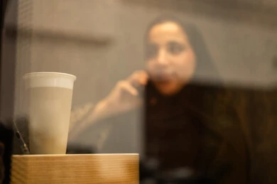 الاطمئنان على الاهل والاصدقاء ، دمج التقنيات المتطورة فى العمل ، امراه عربيه خليجيه سعوديه ترتدي العباءه والحجاب تجلس فى غرفة استراحة العمل تستخدم الهاتف المحمول ، مهن ووظائف نسائية ، العمل في القطاع الإداري والمكتبي