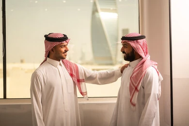 التركيز والعمل المتقن, شرح واعطاء الخبرات بين الزملاء،الحوارات والنقاشات ضمن الفريق,تطوير الاعمال والشركات, اجتماع عمل وانجاز المشاريع, مناقشة الخطط وشرح مهام الاعمال, زملاء عمل عرب سعوديين خليجيين يرتدون الزى التقليدي والشماغ يتبادلان الحديث