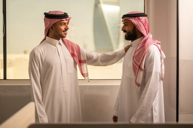 شرح واعطاء الخبرات بين الزملاء، التركيز والعمل المتقن, الحوارات والنقاشات ضمن الفريق,تطوير الاعمال والشركات, اجتماع عمل وانجاز المشاريع, مناقشة الخطط وشرح مهام الاعمال, زملاء عمل عرب سعوديين خليجيين يرتدون الزى التقليدي والشماغ يتبادلان الحديث