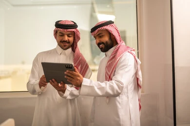 Team discussions and dialogues, using a tablet to accomplish tasks, focus and meticulous work, business and company development, Arab Gulf Saudi employees sitting in the office, discussing project plans, explaining business tasks.