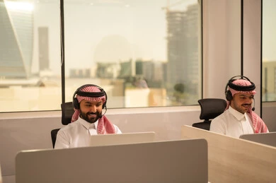 تطوير الاعمال والشركات, أماكن مخصصة لكل موظف في الشركة، التركيز والعمل المتقن, الحوارات والنقاشات ضمن الفريق, اجتماع عمل وانجاز المشاريع, مناقشة الخطط وشرح مهام الاعمال, زملاء عمل عرب سعوديين خليجيين يرتدون الزى التقليدي والشماغ  وسماعات الرأس يستخدمون الحاسوب المحمول