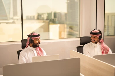 الحوارات والنقاشات ضمن الفريق, أماكن مخصصة لكل موظف في الشركة، التركيز والعمل المتقن,تطوير الاعمال والشركات, اجتماع عمل وانجاز المشاريع, مناقشة الخطط وشرح مهام الاعمال, زملاء عمل عرب سعوديين خليجيين يرتدون الزى التقليدي والشماغ  وسماعات الرأس يستخدمون الحاسوب المحمول