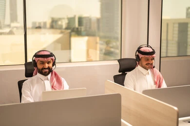 التركيز والعمل المتقن, أماكن مخصصة لكل موظف في الشركة،الحوارات والنقاشات ضمن الفريق,تطوير الاعمال والشركات, اجتماع عمل وانجاز المشاريع, مناقشة الخطط وشرح مهام الاعمال, زملاء عمل عرب سعوديين خليجيين يرتدون الزى التقليدي والشماغ  وسماعات الرأس يستخدمون الحاسوب المحمول