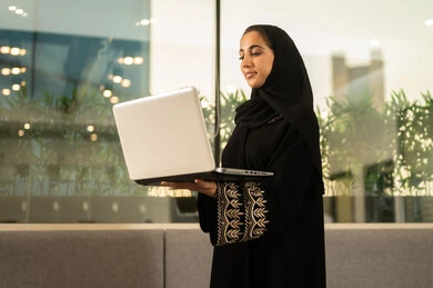 اجتماع عمل اون لاين وانجاز المشاريع, العمل في المكاتب والشركات ، التركيز والعمل المتقن, الحوارات والنقاشات ضمن الفريق,تطوير الاعمال والشركات, مناقشة الخطط وشرح مهام الاعمال, موظفه عربيه خليجيه سعوديه ترتدي العباءه والحجاب تستخدم الحاسوب المحمول