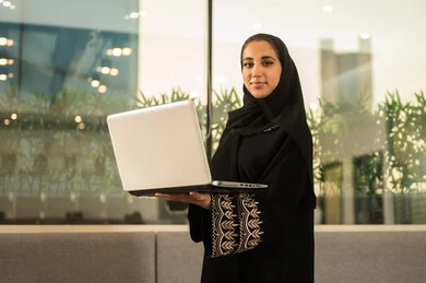 مناقشة الخطط وشرح مهام الاعمال, اجتماع عمل اون لاين وانجاز المشاريع, العمل في المكاتب والشركات ، التركيز والعمل المتقن, الحوارات والنقاشات ضمن الفريق,تطوير الاعمال والشركات, موظفه عربيه خليجيه سعوديه ترتدي العباءه والحجاب تستخدم الحاسوب المحمول