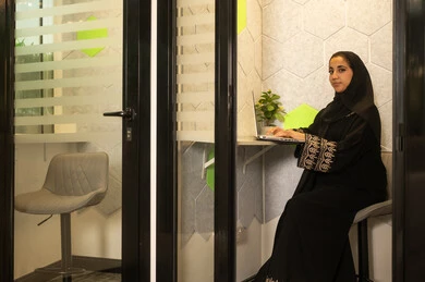 Online work meeting and project completion, working in offices and companies, focus and meticulous work, dialogues and discussions within the team, business and company development, discussing plans and explaining work tasks, an Arab Gulf Saudi female employee wearing an abaya and hijab using a laptop.