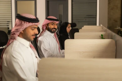 زملاء عمل عرب سعوديين خليجيين يرتدون الزى التقليدي والشماغ يستخدمون الحاسوب المحمول، أماكن مخصصة لكل موظف في الشركة، التركيز والعمل المتقن, الحوارات والنقاشات ضمن الفريق,تطوير الاعمال والشركات, اجتماع عمل وانجاز المشاريع, مناقشة الخطط وشرح مهام الاعمال