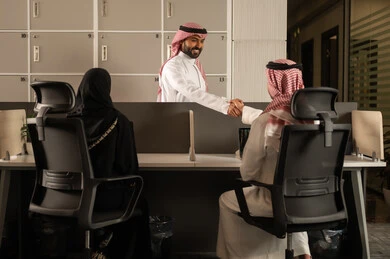Designated spaces for each employee in the company, focus and meticulous work, dialogues and discussions within the team, business and company development, work meetings and project completion, discussing plans and explaining job tasks, Arab Saudi Gulf colleagues using laptops.