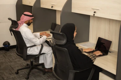 Focus and meticulous work, designated places for each employee in the company, dialogues and discussions within the team, business and company development, work meetings and project completion, discussing plans and explaining work tasks, Arab Saudi Gulf colleagues using laptops.