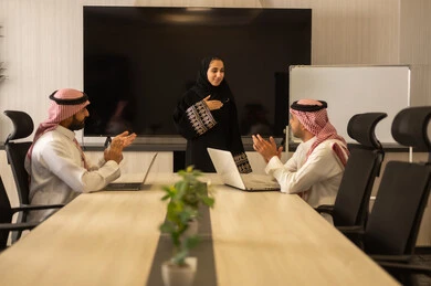 Saudi employees using a laptop, happily explaining the required tasks, Arab Saudi Gulf colleagues in a meeting to study the project and goals accurately, cooperation and understanding among the team, exchanging experiences and successful agreements, organizing and managing work objectives, a comfortable work environment.