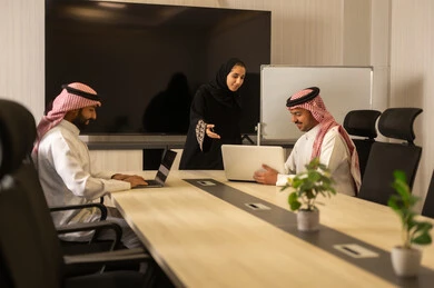 Arab Saudi Gulf colleagues in a meeting to study the project and objectives in detail, cooperation and understanding among the team, exchanging experiences and successful agreements, organizing and managing work goals, a comfortable work environment, Saudi employees using a laptop, happily explaining the required tasks.