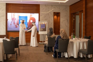 The presence of new colleagues at a meeting, a group of Emirati Gulf Arab employees learning work methods and professional development, cooperation and understanding among colleagues, and setting strategic plans to achieve goals, holding a meeting inside the company headquarters, teamwork and team spirit.
