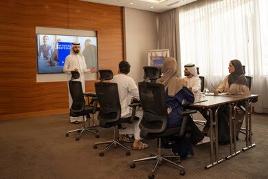 Presenting a presentation on the display screen to clarify and understand the plan, a group of Arab Gulf Emirati employees learning work methods and professional development, cooperation and understanding among colleagues, and setting strategic plans to achieve goals, holding a meeting inside the company headquarters, teamwork and team spirit.