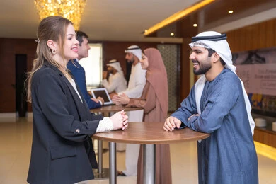 التخطيط الاستراتيجي والتنظيم لتحقيق الأهداف، التعارف وبناء العلاقات الاجتماعية، شاب عربي خليجي اماراتي يناقش  اساليب العمل والتطوير المهني مع سيدة اعمال اجنبية، عقد الصفقات الجديدة عقد اجتماع داخل مقر الشركة، العمل الجماعي وروح الفريق، خلفية رجال اعمال
