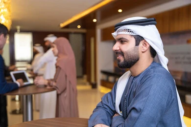 Setting strategic plans to achieve goals, concluding successful agreements and business deals, discussion and understanding among employees, holding a meeting inside the company headquarters, office professions and jobs, attention to elegance and external appearance, an Arab Gulf Emirati man wearing the ghutrah and kandura discussing work methods.