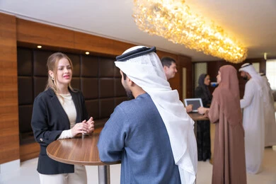 Signing new deals, strategic planning and organization to achieve goals, networking and building social relationships, a young Emirati Arab man discussing work methods and professional development with a foreign businesswoman, holding a meeting inside the company headquarters, teamwork and team spirit, background of businessmen.