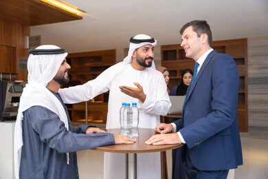 مفهوم الإدارة المتعاونة، النقاش والتفاهم بين الموظفين، تبادل الخبرات والمعلومات لتحقيق الاهداف، التخطيط الاستراتيجي والتنظيم لتحقيق الأهداف، عقد الصفقات الجديدة، مجموعة رجال عربيين خليجيين اماراتيين يناقشون اساليب العمل والتطوير المهني مع سيد اعمال اجنبية
