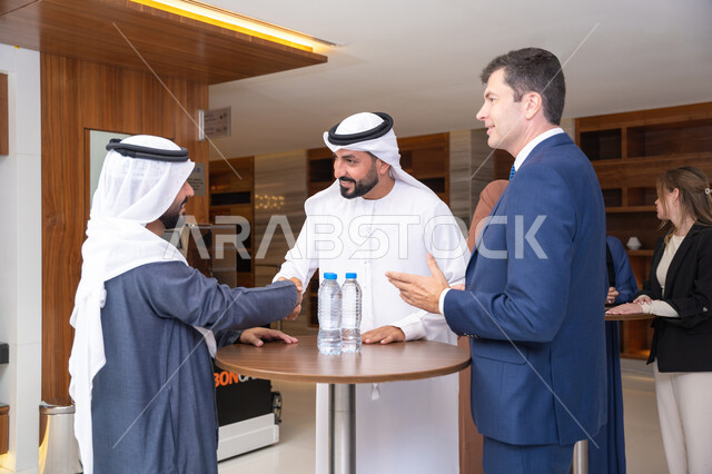 ود وصداقة بين فريق العمل، النقاش والتفاهم بين الموظفين، تبادل الخبرات والمعلومات لتحقيق الاهداف، التخطيط الاستراتيجي والتنظيم لتحقيق الأهداف، عقد الصفقات الجديدة، مجموعة رجال عربيين خليجيين اماراتيين يناقشون اساليب العمل والتطوير المهني مع سيد اعمال اجنبية