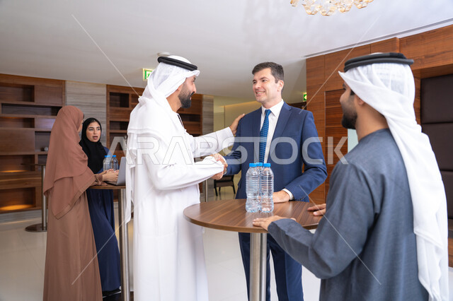 الموافقة على المشاريع التجارية،  النقاش والتفاهم بين الموظفين، تبادل الخبرات والمعلومات لتحقيق الاهداف، التخطيط الاستراتيجي والتنظيم، عقد الصفقات الجديدة، مجموعة رجال عربيين خليجيين اماراتيين يناقشون اساليب العمل والتطوير المهني مع سيد اعمال اجنبية