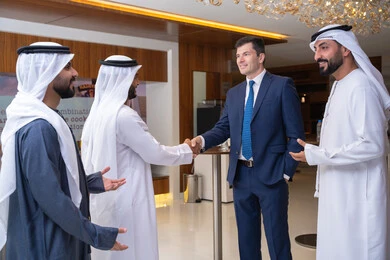 Wearing traditional clothing, strategic plans to achieve goals, discussion and understanding among employees, holding a meeting within the company, office professions and jobs, attention to elegance and external appearance, a group of Arab Gulf Emirati businessmen discussing work methods and professional development with a foreign businesswoman.