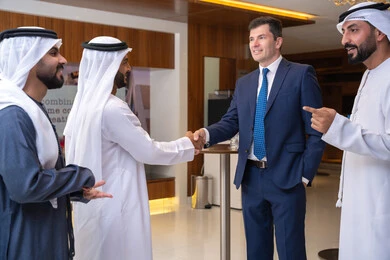 حوارات ونقاشات عمل, الخطط الاستراتيجية لتحقيق الأهداف، النقاش والتفاهم بين الموظفين، عقد اجتماع داخل الشركة، مهن ووظائف مكتبية، الاهتمم بالاناقة والمظهر الخارجي، مجموعة رجال أعمال عربيين خليجيين اماراتيين يناقشون اساليب العمل والتطوير المهني مع سيد اعمال اجنبية