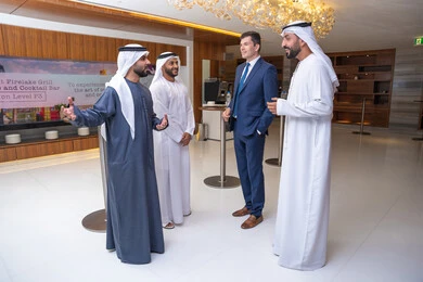 الاهتمام المظهر الخارجي، النقاش والتفاهم بين الموظفين، التشارك في إنجاز الاعمال, الخطط الاستراتيجية لتحقيق الأهداف، عقد اجتماع داخل الشركة، مهن ووظائف مكتبية، مجموعة رجال أعمال عربيين خليجيين اماراتيين يناقشون اساليب العمل والتطوير المهني مع سيد اعمال اجنبية