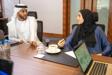 Dialogue and understanding among employees, cooperation between Emirati companies, unity and teamwork, professions and office jobs, using a display screen for clearer explanations, ensuring a clear and comprehensive understanding of the work, strategic plans to achieve goals, a group of businessmen discussing work methods and professional development.