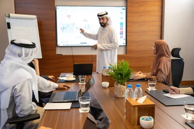 جهاز الحاسوب المحمول متابعة مهام العمل، النقاش والتفاهم بين الموظفين، الخطط الاستراتيجية لتحقيق الأهداف، عقد اجتماع داخل الشركة، مهن ووظائف مكتبية، رجل عربي خليجي اماراتي يشرح اساليب العمل والتطوير المهني لمجموعة من الاشخاص العرب والاجانب