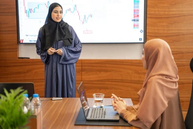 التعاون بين الشركات الاماراتية، الوحدة والعمل الجماعي، مهن ووظائف نسائية، استخدام شاشة العرض لشرح اوضح، ضمان فهم واضح وشامل للاعمال، النقاش والتفاهم بين الموظفين، الخطط الاستراتيجية لتحقيق الأهداف، إمراة عربية خليجية اماراتية تشرح اساليب العمل والتطوير المهني