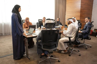 Inside the company, a meeting was held on women's professions and jobs, using a display screen for clearer explanations, ensuring a clear and comprehensive understanding of the work, discussion and understanding among employees, strategic plans to achieve goals, an Arab Gulf Emirati woman explaining work methods and professional development to a group of Arab and foreign individuals.
